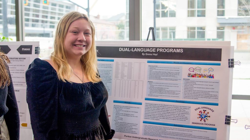 Emma Heyl smiling in front of her project poster.